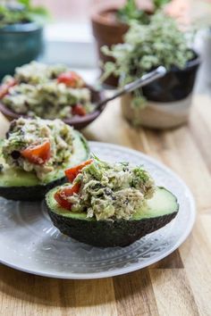 avocado stuffed with tuna and tomatoes on a plate next to potted plants