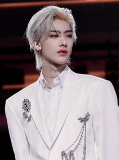 a man with grey hair wearing a white suit and red lipstick on the runway at a fashion show