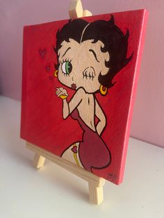 a small wooden easel with a painting of a woman on it's side