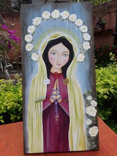 a painting of a woman with flowers around her neck and hands, on a wooden table