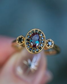 a close up of a person holding a ring with a blue and brown stone in it