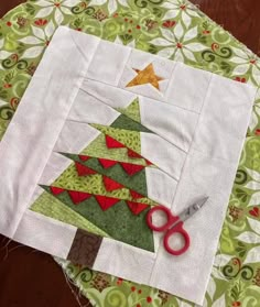 a pair of scissors sitting on top of a table next to a quilted christmas tree