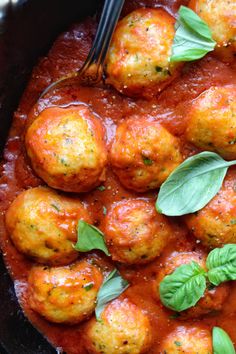 meatballs in tomato sauce with basil leaves on top and a fork sticking out of it