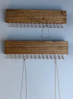 two wooden pegs are hanging on the wall and some beads hang from it's hooks