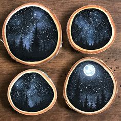 four painted wooden bowls with trees and the moon in them on a wood table top