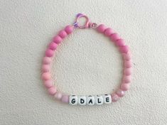 a pink beaded bracelet with the word godie spelled in white letters on it