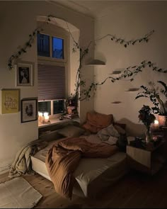 an unmade bed sitting next to a window in a room with plants on the wall