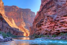 a river flowing through a canyon surrounded by tall mountains and cliffs in the distance with water running between them