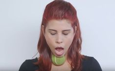 a woman with red hair making a funny face while holding a green object in her mouth