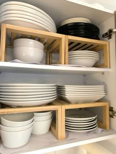 white dishes are stacked on wooden shelves in the cupboards, with black and white plates