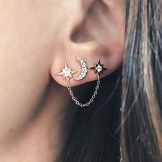 a close up of a person wearing ear piercings with stars and moon designs on them