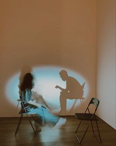 a person sitting in a chair next to a projected image of a man and woman