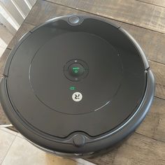 a robot vacuum on the floor with its lid open and buttons pointing to the left