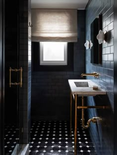 a black and white tiled bathroom with gold fixtures