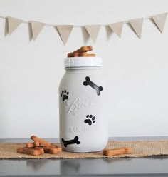 a white mason jar with dog paw prints on it and some cinnamon sticks in front of it