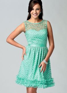 a woman in a short green dress posing for a picture with her hands on her hips