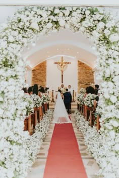 the bride and groom are walking down the aisle at their wedding ceremony in front of an altar with white flowers