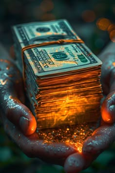 a stack of money being held in the palm of someone's hands with water droplets on them