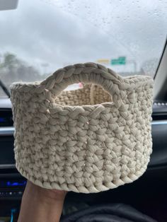 a person holding up a basket in their hand on the steering wheel of a car