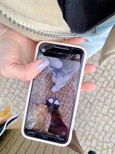 a woman holding up her cell phone to take a selfie with the reflection of another person's feet