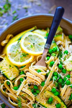 a bowl filled with pasta, peas and lemon slices