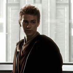 a young man wearing headphones standing in front of a window