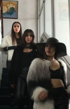 three women are standing on the stairs wearing hats and fur stolers, one is holding a purse