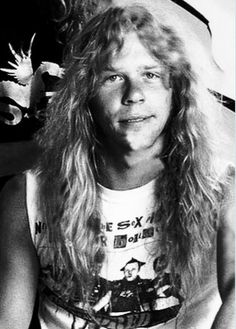 an old black and white photo of a man with long hair wearing a t - shirt