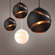 three black and white globe lights hanging from the ceiling in a room with grey walls