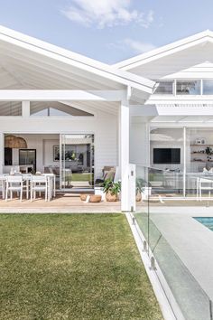 a white house with a pool in the front yard and an outdoor dining area on the other side