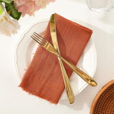 a plate with two forks and a napkin on it next to a basket filled with flowers