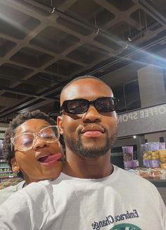 a man and woman wearing glasses standing in front of a produce section at a grocery store