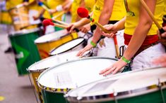 people in yellow shirts are playing drums on the street