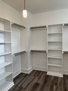 an empty walk in closet with white shelving