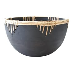 a black bowl with bamboo sticks sticking out of the top and sides, on a white background