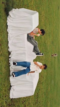 two men standing next to each other on top of a grass covered field