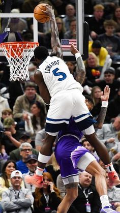 two basketball players colliding over each other in front of an arena full of people