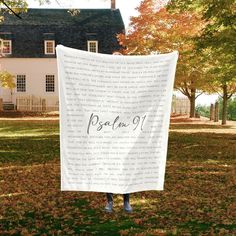 a person standing in front of a house holding a white blanket with the word pish on it