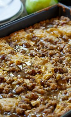 a casserole dish with meat and apples in the background