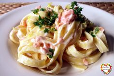 a white plate topped with pasta covered in sauce and garnished with parsley