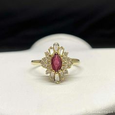 a gold ring with a red stone surrounded by white and clear stones on top of it