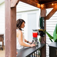 a woman standing on a porch next to a juicer