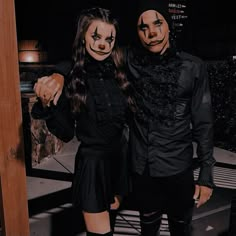 two people with painted faces standing next to each other wearing black clothes and masks on their faces