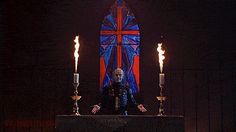 a man sitting on a bench with candles in front of him and a stained glass window behind him