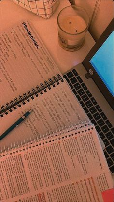 an open laptop computer sitting on top of a desk next to a notebook and pen