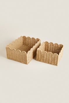 two woven baskets sitting side by side on a white surface, one is empty and the other has no lid