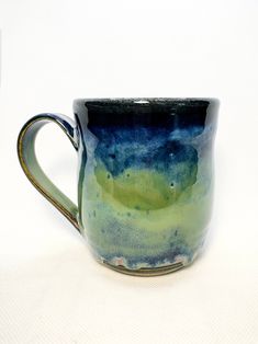 a blue and green coffee cup sitting on top of a white table