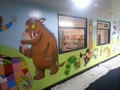 a wall painted with children's pictures and cartoon characters on the side of it