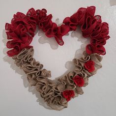 a heart shaped wreath with red flowers and burlocks