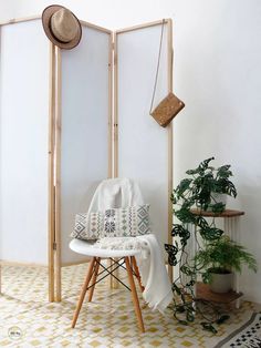 a room divider with a chair, potted plants and a hat on it